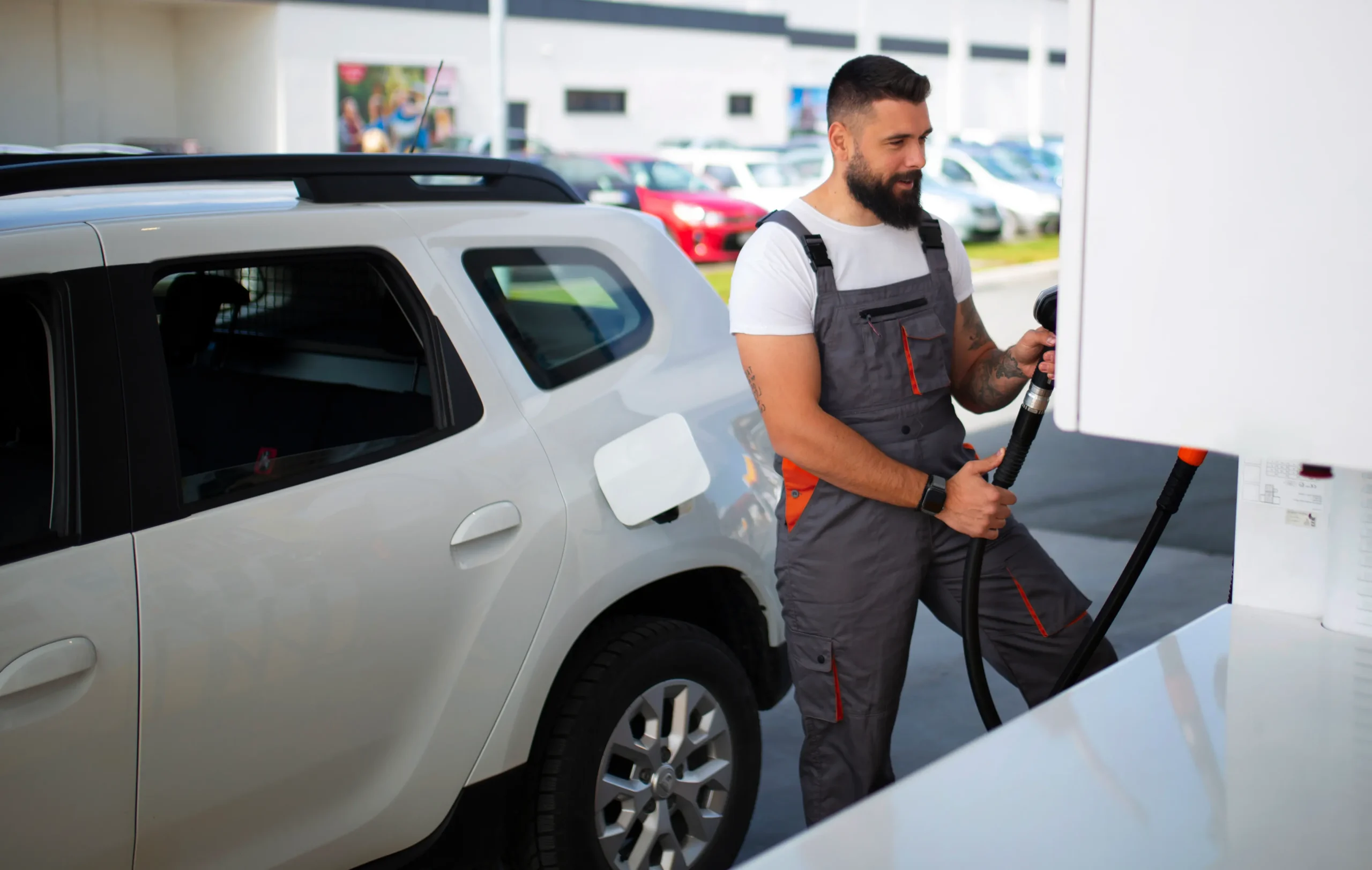 Empleado de gasolinera llenando el coche de combustible. y siguiendo protocolos contenidos en el software para gasolineras de Limbit